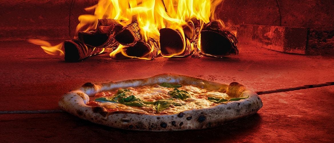 A pizza cooked fresh in a traditional pizza oven