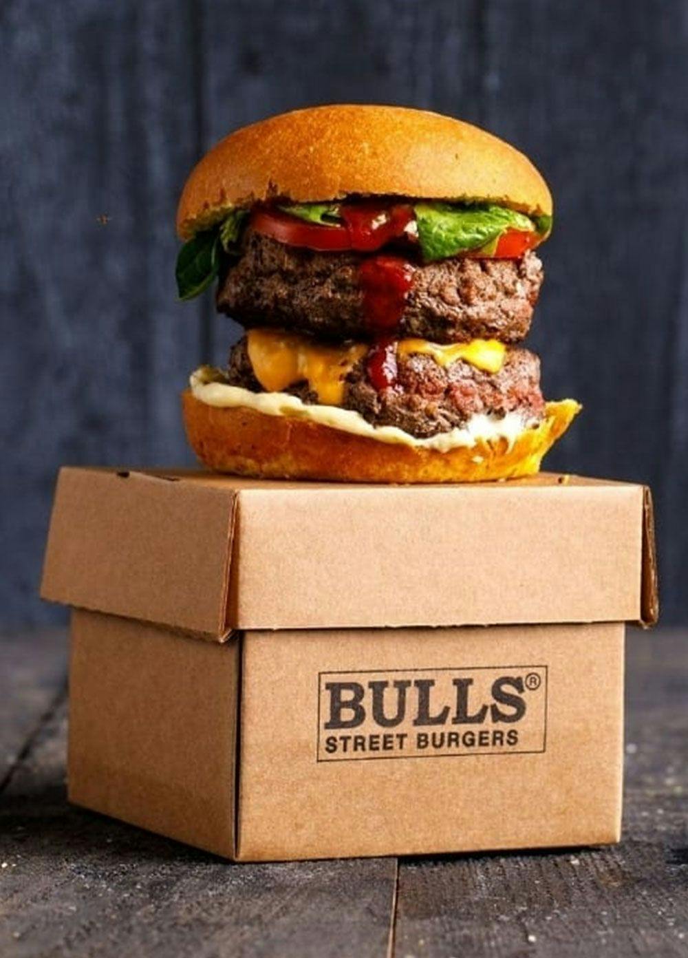 A double patty delight burger with Bulls Street Burgers branded packaging.