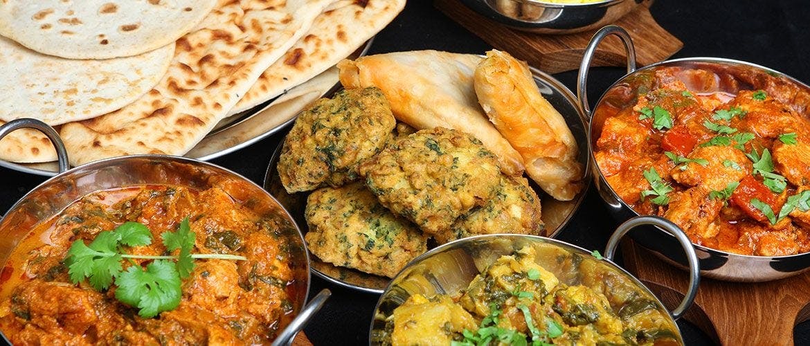 A selection of curries with naan bread on the side.