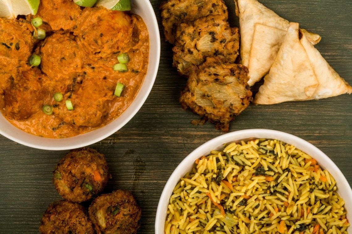 A tasty Indian curry, samosas, onion bhajis and a bowl of rice.