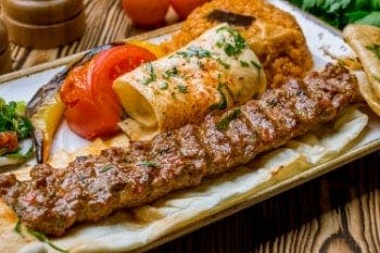 A grilled kebab served with tomato and rice