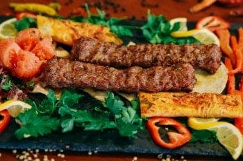 Two grilled kebabs served with salad