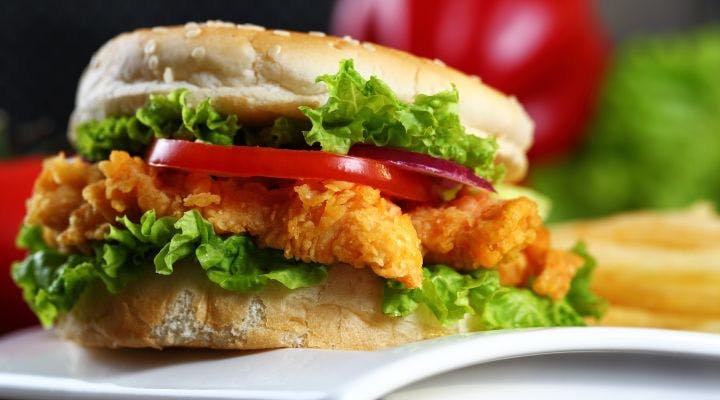 A crispy chicken fillet burger in a bun with lettuce and tomato