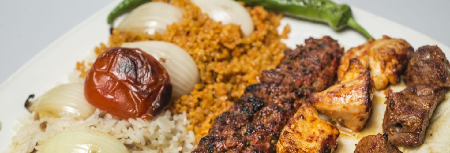 A selection of grilled kebabs, served with rice, onions and a chilli.