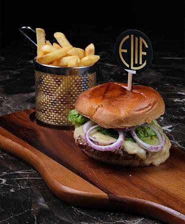 Loaded Beef Burger with a portion of fries on a wooden table