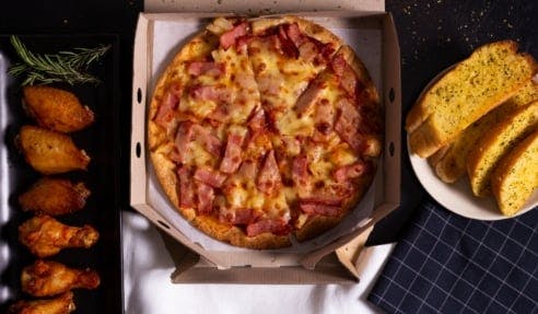 Ham pizza served with chicken wings and garlic bread