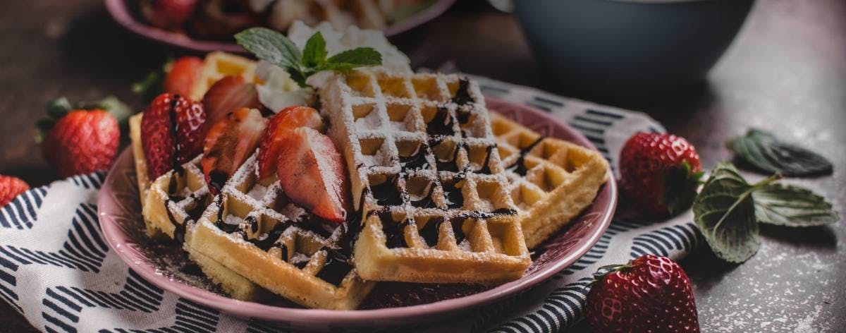 Waffles filled with chocolate and strawberries, served on a well-designed plate.