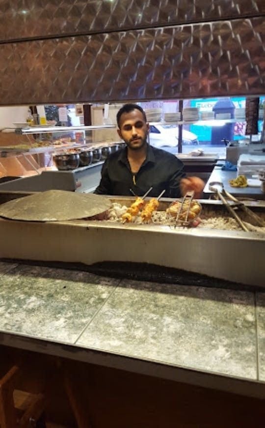 Inside Levante Lewisham (Restaurant), a customer is serving himself at the open kitchen.