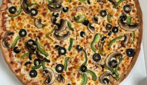 A vegetable pizza with mushrooms, olives, green peppers, and corn.