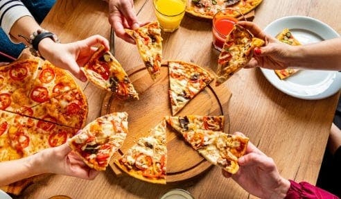 Margherita Pizza with onions on a table, being shared by people